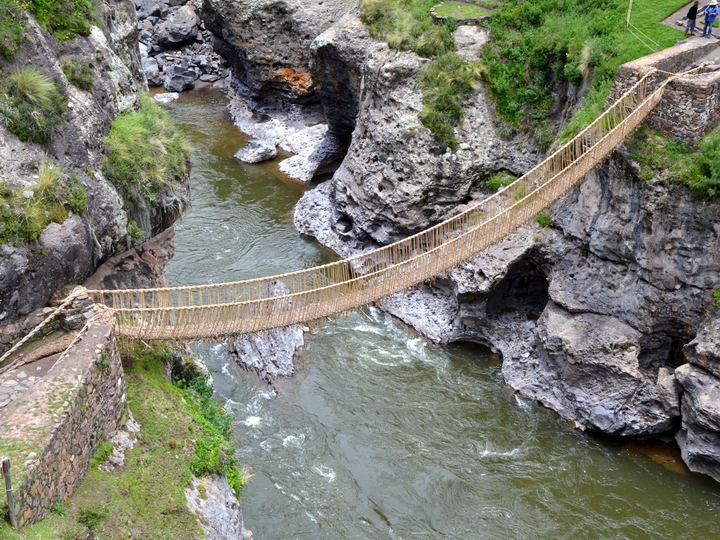 The Q'eswachaka rope suspension bridge, woven from grass, hanging across a rocky gorge above the rushing Apurímac River in Peru